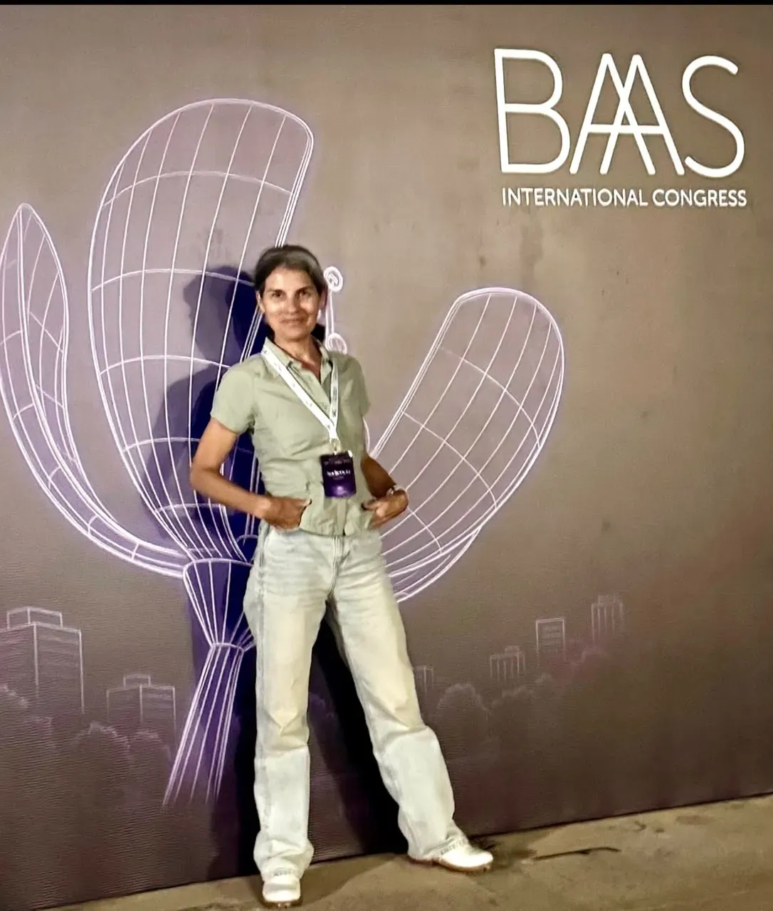 Marcela frente al cartel del BAAS International Congress, con la credencial colgada